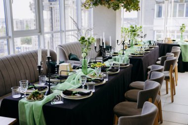 Şatafatlı yeşil ve siyah yemek masası. Mumlar, çiçekler ve cam eşyalar. Yüksek kalite fotoğraf