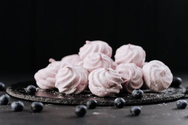 Tahta tabakta yaban mersinli pembe kremalar, koyu arka plan, şeker tozu. Yüksek kalite fotoğraf