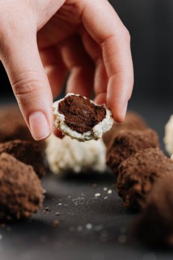 El ele tutuşmak, hindistan cevizi mantarı, koyu çikolata dolgulu, makro siyah. Yüksek kalite fotoğraf