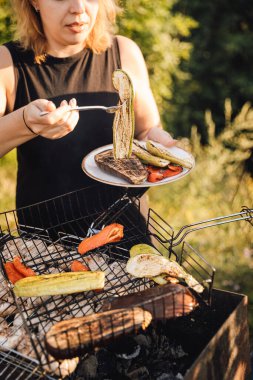 Barbeküden ızgara sebze servis eden bir kadın, yaz güneşinde dışarıda tabağı tutan bir kadın. Yüksek kalite fotoğraf