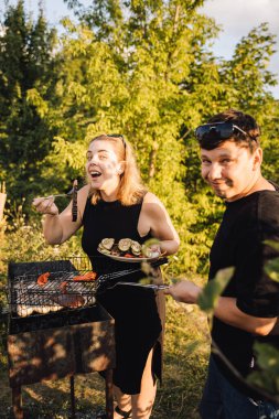 Dışarıda ızgara yapan birkaç sebze, altın saatinde barbekü yapan bir kadın. Yüksek kalite fotoğraf