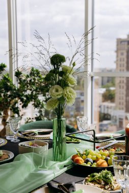 Şehir manzaralı zarif ziyafet masasında yeşil çiçekli süs, doğal ışık. Yüksek kalite fotoğraf