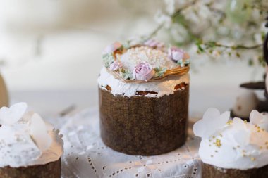 Paskalya pastaları ve yumurtalar dantel masanın üzerinde bahar çiçekleri dalları, yumuşak gün ışığı. Yüksek kalite fotoğraf