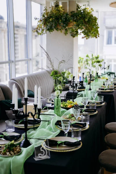 Zarif siyah ve yeşil masa manzarası, mumlar, yer ayarları ve cam eşyalar. Yüksek kalite fotoğraf