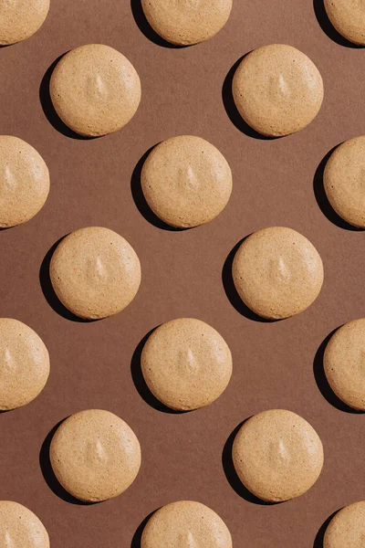 Kahverengi arka planda sert gölgeli bej badem kurabiyelerinin kusursuz deseni. Yüksek kalite fotoğraf
