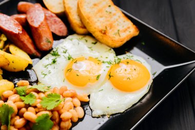 Yağda yumurta, sosis, patates, fasulye ve tost ile dolu kahvaltı tabağı. Yüksek kalite fotoğraf