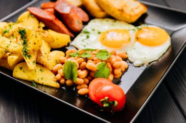 Yağda yumurta, sosis, patates, fasulye ve tost ile dolu kahvaltı tabağı. Yüksek kalite fotoğraf