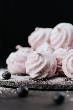 Böğürtlenli pembe kremalı kurabiye ve kayrak üzerine düşen şeker, koyu arkaplan. Yüksek kalite fotoğraf