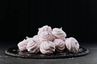 Tahta tabakta pembe kremalı kurabiye, koyu arka plan, pudra şekeri. Yüksek kalite fotoğraf