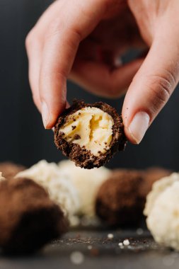 Isırılmış çikolatalı trüf mantarı, kremalı, koyu arka planda makro. Yüksek kalite fotoğraf