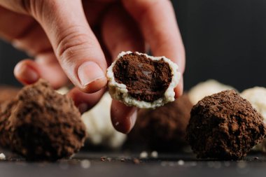 El ele tutuşmak, hindistan cevizi mantarı, koyu çikolata dolgulu, makro siyah. Yüksek kalite fotoğraf