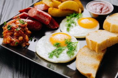 Kahvaltı tabağı, kızarmış yumurta, sosis, patates dilimleri ve ekmek, üst manzara. Yüksek kalite fotoğraf