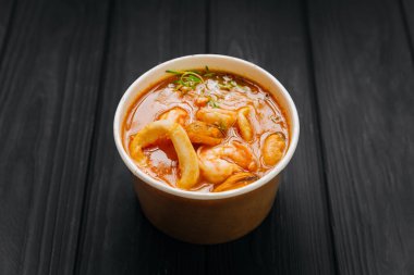 Tom karides, midye ve mürekkep balığıyla Kraft kasesinde koyu ahşap masada leziz bir çorba. Yüksek kalite fotoğraf