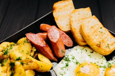 Kapalı kahvaltı, kızarmış yumurta, sosis, kızarmış patates ve siyah tabakta tost. Yüksek kalite fotoğraf