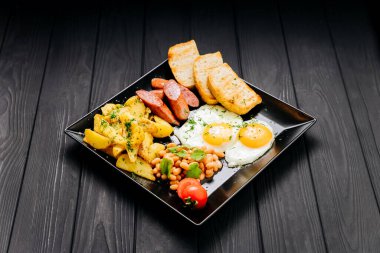 Yağda yumurta, sosis, patates, fasulye ve tost ile dolu kahvaltı tabağı. Yüksek kalite fotoğraf