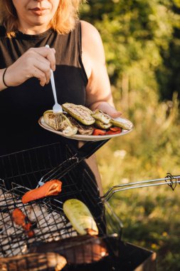 Barbeküden ızgara sebze servis eden bir kadın, yaz güneşinde dışarıda tabağı tutan bir kadın. Yüksek kalite fotoğraf