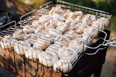 Mantarlar ızgarada ızgara sepetinde kızartılıyor, gün batımında dışarıda pişiriliyor. Yüksek kalite fotoğraf