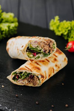 Izgara ton balıklı tortilla, yeşillik, sos ve domatesli. Yüksek kalite fotoğraf