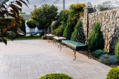 Bahçe bahçesinde işlenmiş demir bankları olan zarif taş duvar terası. Yüksek kalite fotoğraf