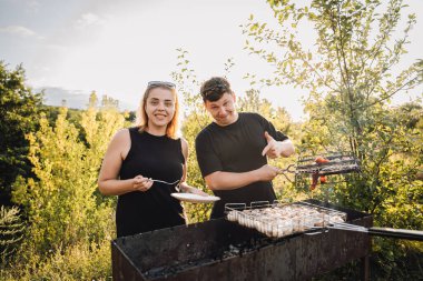 Gün batımında dışarıda sebze ızgara yapan çiftler yaz barbeküsünde yemek tadıyorlar. Yüksek kalite fotoğraf