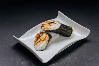 Hand roll sushi with salmon cucumber and rice wrapped in nori on white plate. High quality photo
