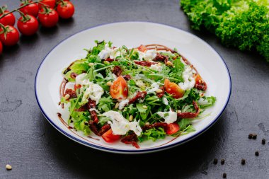 Kurutulmuş domatesli taze yeşil salata ve tabakta kremalı sos. Yüksek kalite fotoğraf