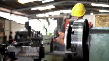 Ağır Sanayi İşçisi dizüstü bilgisayarlı adam çelik plakayı keserek ve ölçerek kontrol ediyor. Arka planda Odaklanmamış Büyük Endüstriyel Fabrika.