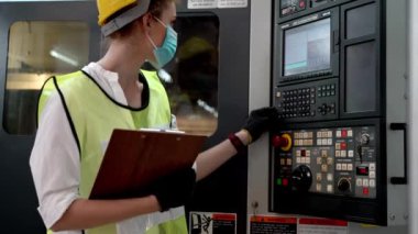 Fabrika Profesyonel Yöneticisi kadın rapor kâğıdıyla ağır makineleri denetliyor ve makinenin etrafında dolanıyor. Üretim endüstrisi için kalite güvencesi. Konsept Mühendisi Güvenlikle çalışıyor.