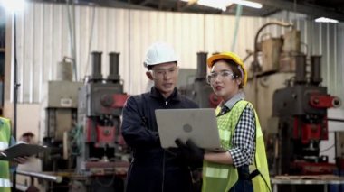 Bir grup fabrika çalışanı tablet bilgisayar ve kağıt dosya raporlarıyla tartışıyor..