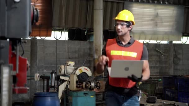 拥有笔记本电脑的重工业工人正在重型机械制造厂前进行检查和控制 背景下的无重点大型工业厂房 — 图库视频影像