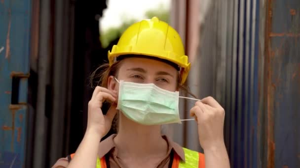 Arbeiterinnen ziehen Schutzmaske und Schutzhelm aus und tragen im Outdoor-Lager grüne reflektierende Schutzanzüge. Konzept der Sicherheitsbranche Arbeiter in Betrieb.