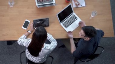 Masada oturan ve ofiste proje tartışan dört iş adamının üst düzey görüntüsü. İş yaşamını ve teknolojiyi kavra.