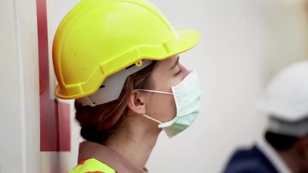 労働者の女性労働者は 屋外倉庫工場での仕事の後にリラックス座っている 保護マスク顔と安全ヘルメットを身に着けている業界の労働者の概念 — ストック動画