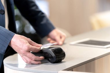 Tezgâhtan almak için kredi kartı tutan müşteriler. Temassız ödeme sistemlerinin teknoloji aygıtıyla para harcaması kavramını kabul et.