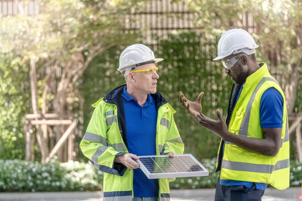 工場労働者技術者の男性は緑の作業スイートのドレスと安全ヘルメットと持続可能な技術のための太陽電池パネルをチェックします 背景または緑の壁の木の性質 — ストック写真