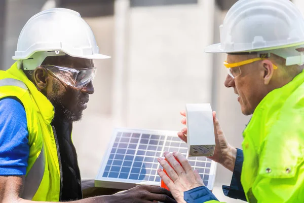 工場労働者技術者の男性は太陽電池パネルを見せてチェックする作業服とヘルメットで持続可能な技術のために コンセプト施工太陽光発電パネル再生可能エネルギー — ストック写真