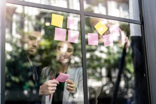 business people brainstorming putting sticky notes on glass window wall in office. Window glass reflection daylight and environment nature. Creative group startup business meeting for new idea.