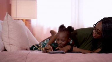 Anne ve çocuk yatak odasında uzanırken birlikte ders çalışıyor. Annesi ona resim çizmeyi öğretirken.