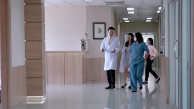 Hastanede, koridorda yürürken maske takan Meşgul Doktorlar konuşuyor. Arka plandaki hasta ve personel koğuşta yürüyor. konsept tıp insanları Modern Temiz Tıp Tesisinde yaşam.