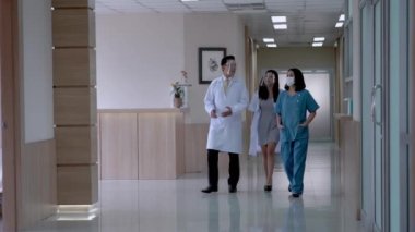 Koridorda yürürken maskeli doktorlar konuşmakla meşgul. Arka plan hastaları ve koğuş bölgesinde yürüyen personel. Modern Temiz Tıp Tesisi 'nde tıp yaşamını kavramsallaştır.