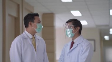 Koridorda dikilirken maskeli doktorlar konuşuyor. Arka plan hastaları ve koğuş bölgesinde yürüyen personel. Modern Temiz Tıp Tesisi 'nde tıp yaşamını kavramsallaştır.