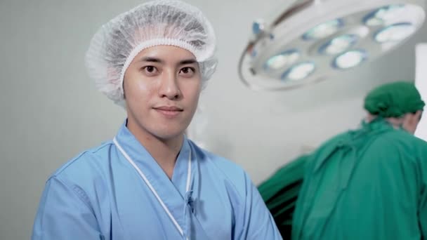 亚洲男子在病人套间里笑着站着 而工作人员和医生在医疗设施的手术室里准备和工作 手术室医院有照明设备 — 图库视频影像