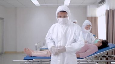 Kişisel koruyucu giysi giyen doktor kendine güveniyor. Hemşireler hastanedeki temiz odada maske takan hastaları muayene ediyorlar. İnsanlarda Covid-19 ya da koronavirüs hastalığı vardı..