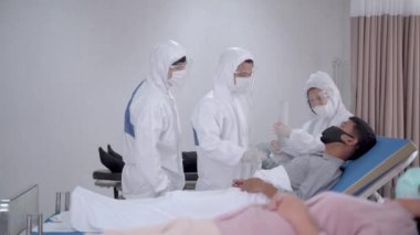 Kişisel koruyucu giysi giyen bir doktor. Hemşireler hastanedeki temiz odada maske takan hastaları muayene ediyorlar. İnsanlarda Covid-19 ya da koronavirüs hastalığı vardı..