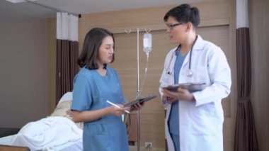 Doktor ve hemşire hasta Asyalı yaşlı bir adamın yatakta dinlenirken gösterdiği semptom ve tedaviyi araştırmak için konuşuyor. Modern hastane odasındaki VIP sınıfında tıbbi tedavi kavramı.