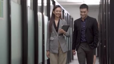 Zeki Asyalı iş adamları ofis koridorunda yürürken haberleri tartışır ve fikir alışverişinde bulunurlar..