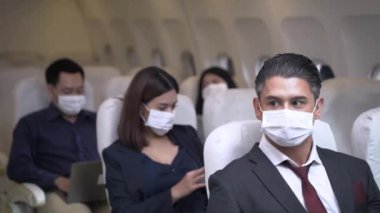 Uçakta oturduktan sonra maske takan işadamı ve yolcular. Sağlık koruması için hava taşımacılığında yeni bir normal kavram.