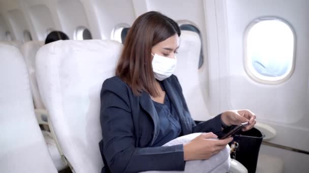 Mujer Asiática Con Mascarilla Facial Usando Smartphone Sentada Silla Avión — Vídeos de Stock