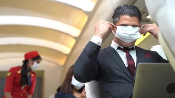 窓の近くの飛行機の椅子に座って顔のマスクをしたビジネスマン 健康保護のための航空輸送の新しい通常の概念 — ストック動画