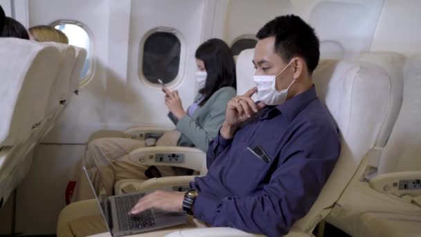 Επιχειρηματίας Μάσκα Προσώπου Χρησιμοποιώντας Φορητό Υπολογιστή Και Κάθεται Καρέκλα Αεροπλάνου — Αρχείο Βίντεο